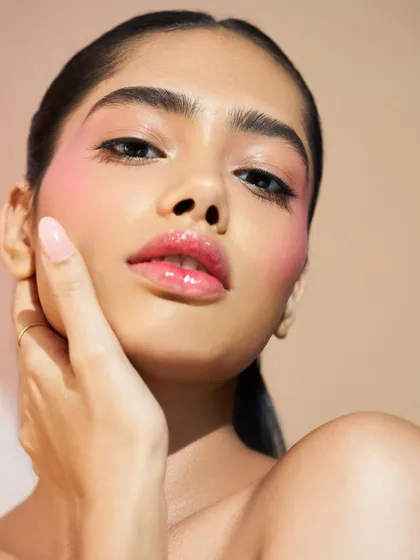 A final shot of this glossy, fresh beauty look. The highlight on the cheek and the glossy lip work together to create a youthful and radiant effect.