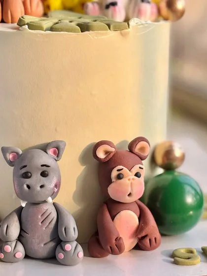A close-up of the hand-molded fondant hippo and monkey from the jungle theme cake, showcasing their cute expressions.