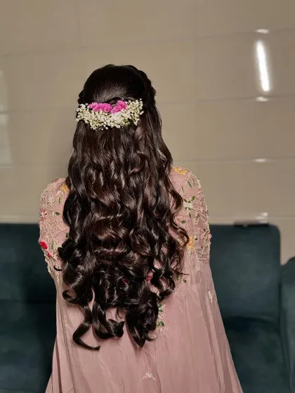 A beautiful half-updo with a crown of fresh baby's breath and pink flowers.