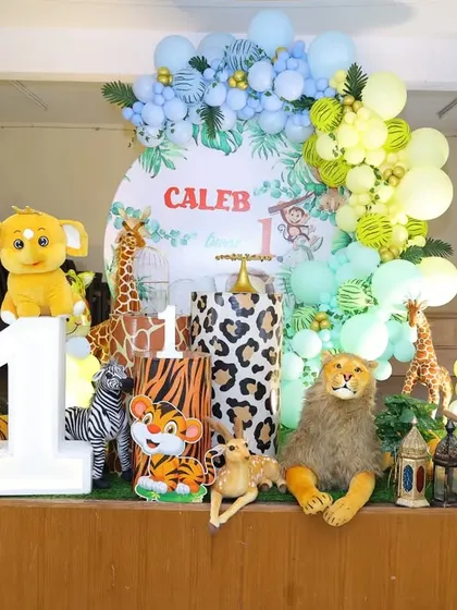 A full stage view of Caleb's jungle party, showing the arrangement of plush animals and balloon columns.