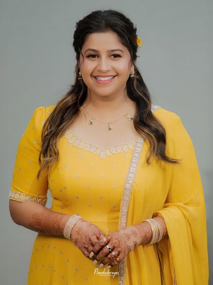 A classic bridal portrait for the Haldi ceremony. The bride's happy smile and the intricate henna on her hands are beautifully highlighted against a simple background.