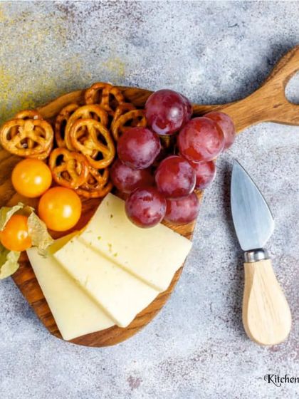 A charming small platter with sliced cheese, pretzels, grapes, and cape gooseberries. This showcases my ability to create delightful arrangements for any scale.