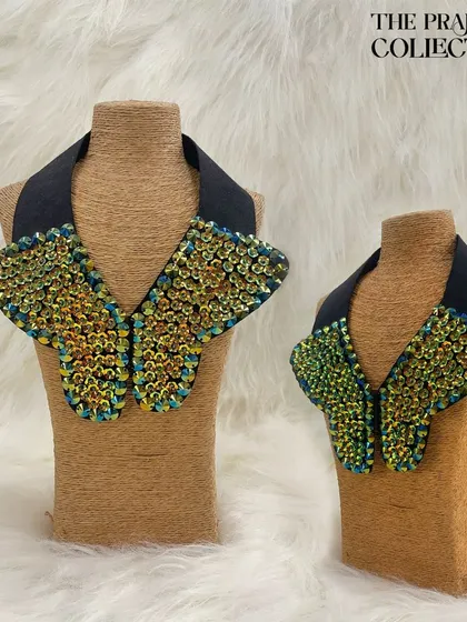 A unique detachable collar featuring a butterfly-wing shape covered in iridescent, textured beadwork. The black base makes the shimmering colors pop, creating a dazzling effect.