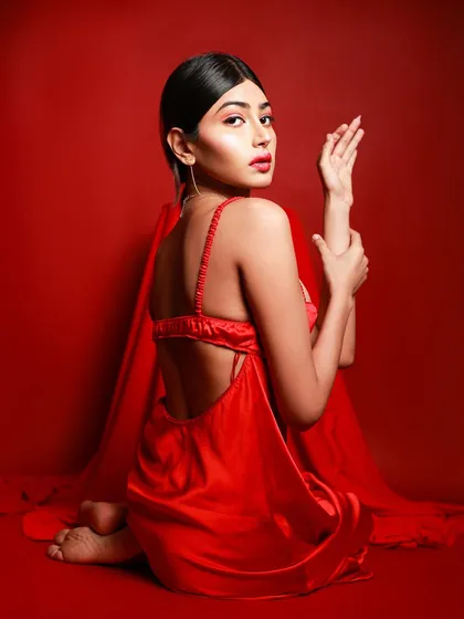 Another powerful pose from the red-on-red series, with the model seated and looking back at the camera, showcasing the backless design of the dress.