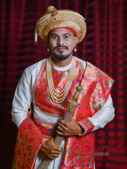 A regal portrait of the groom in a traditional Peshwai-style outfit, complete with a turban and ceremonial sword.