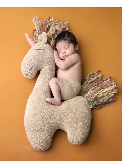 Another angle of our sweet unicorn theme, set against a warm, solid-colored background to keep the focus on the baby and the magical creature.