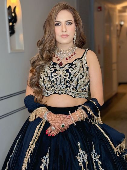 A glamorous reception look in a stunning black and gold lehenga. The makeup is bold and sophisticated, with a focus on the eyes.