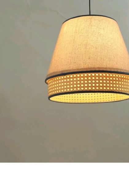 This pendant light combines a fabric upper shade with a lower band of woven cane. The design provides both soft, diffused light from the top and a patterned glow from the bottom, offering a unique and sophisticated lighting solution.