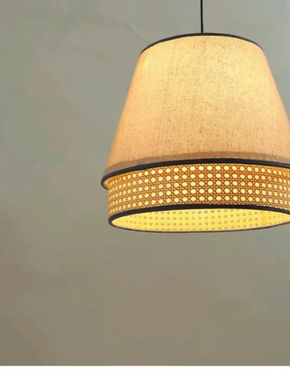 This pendant light combines a fabric upper shade with a lower band of woven cane. The design provides both soft, diffused light from the top and a patterned glow from the bottom, offering a unique and sophisticated lighting solution.