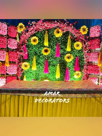 A Mehendi ceremony should be full of joy and color. This setup features a vibrant backdrop of sunflowers and pink florals against a green wall, creating a cheerful and picture-perfect spot for the bride.