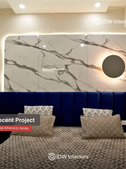 A stunning bedroom in Capital Athena featuring a bold blue headboard against a marble-effect wall panel with a unique back-lit circular accent.