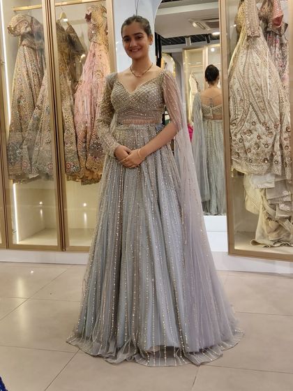 A happy client looking ethereal in a light grey lehenga with delicate silver embroidery and a sheer cape. It's a perfect example of modern, understated elegance.