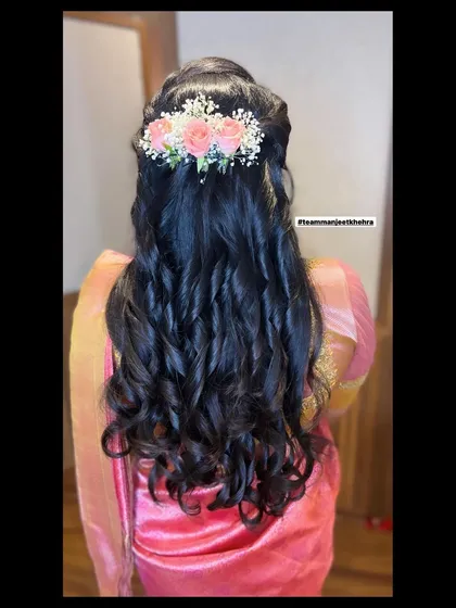 A hairstyle can complete the entire look. For this reception style, I created soft, cascading curls and adorned them with fresh pink roses and baby's breath for a romantic and feminine touch that perfectly matched her pink silk saree.