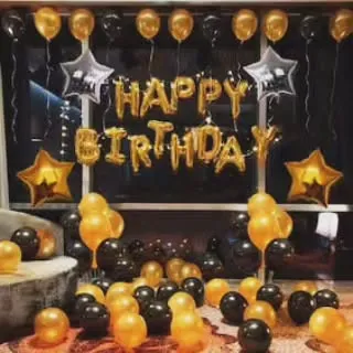 This is my popular black and gold birthday theme. The setup includes a large 'HAPPY BIRTHDAY' foil banner against a dark backdrop, star-shaped foils, and dozens of balloons covering the floor and ceiling to create a full party atmosphere.