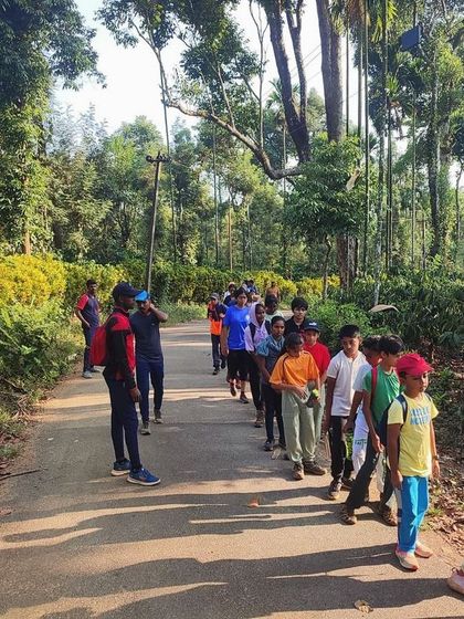 Participants on a trek through the lush green pathways of Coorg, surrounded by diverse plant life.