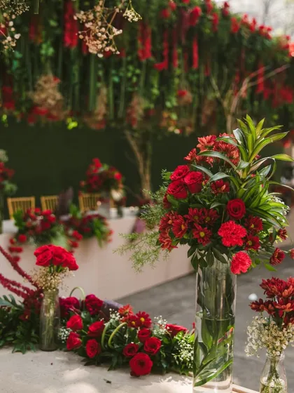 A beautiful composition of various floral arrangements on a buffet or welcome table. The mix of tall vases and low runners creates visual interest and depth, showcasing a rich and abundant floral theme for any corporate event.