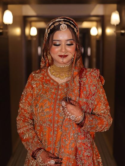 My gorgeous Nikkah bride Ashana in a stunning orange and red outfit. Her makeup is soft and glowing, with a beautiful red lip and defined eyes.
