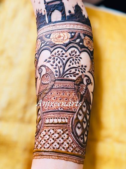 A close-up of an arm band featuring two peacocks in a pot, a unique and artistic motif.