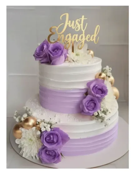 A beautiful lilac and white two-tier cake for an engagement celebration. This is my signature eggless chocolate truffle cake, decorated with fresh purple roses and delicate baby's breath.