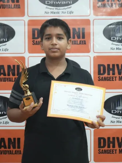 A student proudly holds his certificate and trophy.