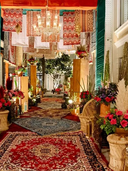 The beautifully layered entrance walkway, with Persian rugs on the floor, hanging from the ceiling, and lining the walls, creating a truly immersive arrival.