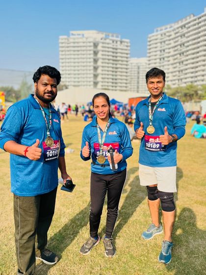 Three happy finishers with their medals, giving a thumbs up to a great race day experience.