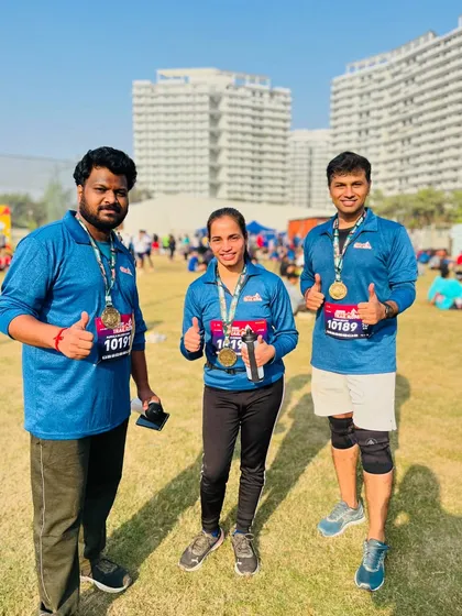 Three happy finishers with their medals, giving a thumbs up to a great race day experience.