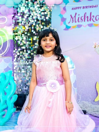 The birthday girl looking like a princess at her mermaid-themed party. The shimmering backdrop and underwater coral props created a magical setting for her special day.