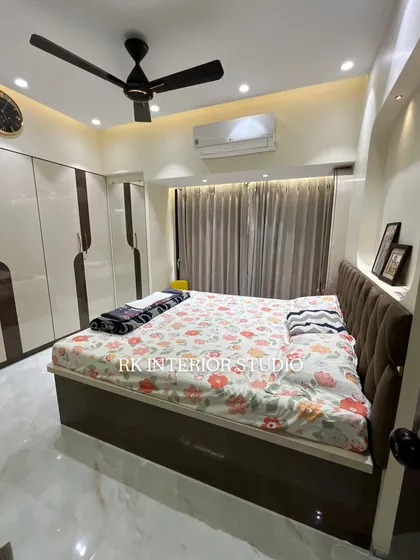 This image shows the complete bed with its tufted headboard and the two-tone wardrobe. The color palette is warm and neutral, creating a calming and restful environment.