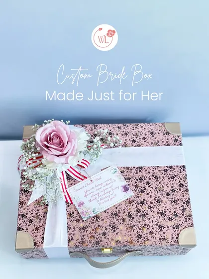 A custom bride box, made just for her. This beautiful floral-printed suitcase is adorned with a personalized note and a silk flower arrangement.