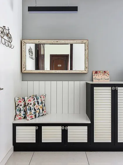 This simple and functional foyer uses a black and white theme that is effortlessly chic. The shoe cabinet features louvered doors, and the bench has a grooved back panel for added detail.