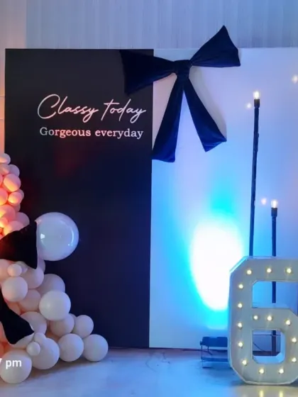 A classy black and white theme for a 60th birthday. The backdrop features a personalized quote, accented with bows, balloons, and large marquee numbers.