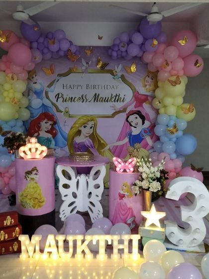 A classic Disney Princess theme for a 3rd birthday, with a backdrop featuring Snow White, Rapunzel, and Ariel, complemented by pastel balloons.