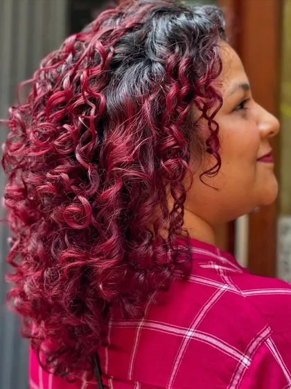 A vibrant, fiery red that makes a bold statement. This color was achieved without any bleach, protecting the integrity of her curls.