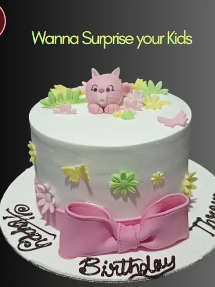 A sweet and simple birthday cake with a cute pink cat, flowers, and a large pink bow. It's a charming design perfect for surprising your kids.