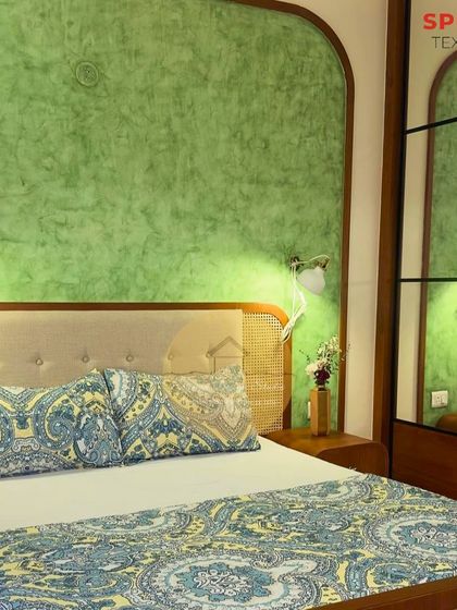 A serene bedroom featuring a dual-tone green textured paint on an arched feature wall. The custom bed has a cane headboard and frame, blending natural materials with a pop of color for a refreshing, ethnic vibe.