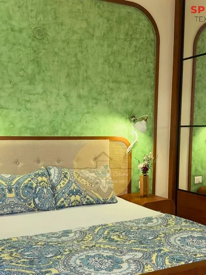 A serene bedroom featuring a dual-tone green textured paint on an arched feature wall. The custom bed has a cane headboard and frame, blending natural materials with a pop of color for a refreshing, ethnic vibe.