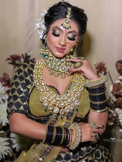A serene portrait of the bride, her eyes lowered, showcasing the complete hair, makeup, and jewelry ensemble.