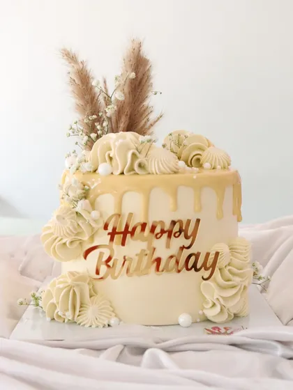 A beautiful boho-inspired cake with a white chocolate drip. I used pampas grass and delicate piped shells to create a design that's perfect for a beachy or rustic theme.