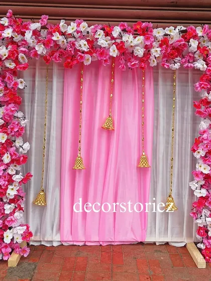 This elegant pink and white ready-to-install makhar is decorated with artificial cherry blossoms and hanging golden bells. The dual-layered curtain adds depth, making it a beautiful frame for your Ganpati idol.
