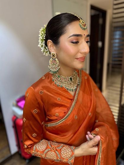 Hanita's gentle smile lights up her face. The minimal makeup ensures her natural beauty is the focus, enhanced by the warm tones of her saree and jewelry.