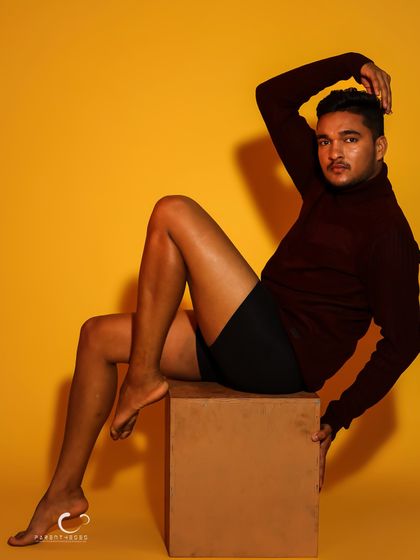 A dynamic seated pose that showcases strength and grace. The lighting highlights the muscle definition, creating a sculpture-like effect.