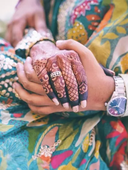 A simple, beautiful moment of connection. The bride's henna-clad hand held by her partner.