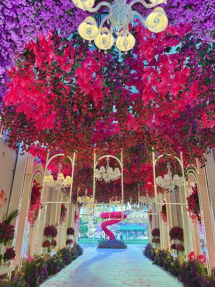 A view looking up through the floral tunnel, where a ceiling of red leaves and hanging chandeliers creates a dramatic and enchanting effect.