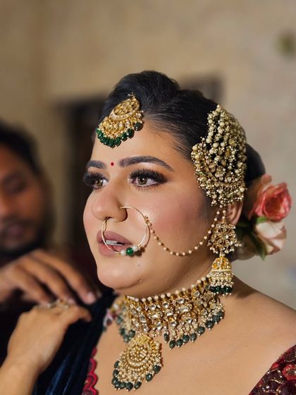 A candid moment during the hairstyling process. The makeup is already looking flawless and ready for the final touches.