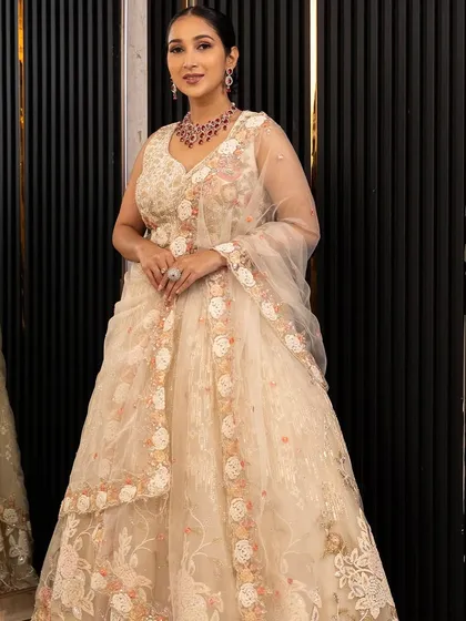 A full look at our elegant ivory floral lehenga. The delicate embroidery and flowing net dupatta create a soft, romantic look perfect for a modern bride.