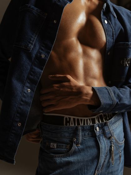 A torso close-up showing the texture of a denim jacket against the skin and the iconic waistband. This type of detailed shot is crucial for highlighting product quality and brand identity.