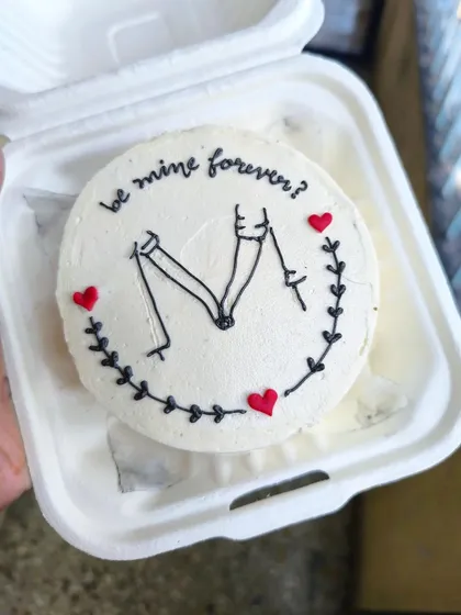 A simple question on a minimalist bento cake can make for the sweetest moment. This design features clean, hand-piped line art of a couple holding hands, perfect for anniversaries, proposals, or just because.