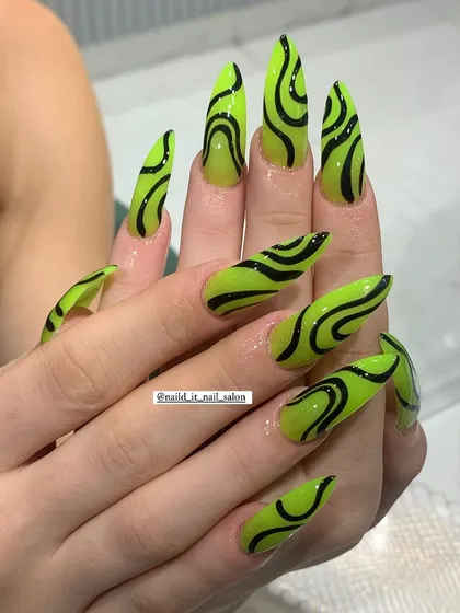 For those who love a bold statement, this design features vibrant neon green gel polish on extra-long stiletto nails. The look is elevated with hand-painted black abstract swirls, creating a graphic and eye-catching style.