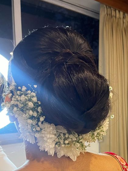 A classic bridal bun adorned with fresh white flowers and baby's breath. This is a timeless and elegant choice for any traditional bride.